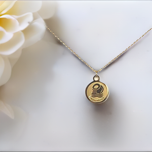 Gold Colored Aquarius Medallion Necklace with a white / beige background and a huge light colored flower next to the necklace