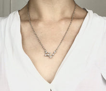 Load image into Gallery viewer, A Silver Taurus Constellation Sign Necklace is worn on a model. 
