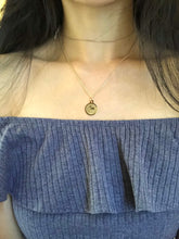 Load image into Gallery viewer, The front side of the gold Aries coin necklace worn on a model
