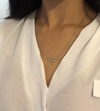 Load image into Gallery viewer, Silver Aries Zodiac Sign Necklace worn on a model. The pendant hit around three fingers below the collar bone. 
