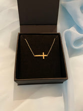 Load image into Gallery viewer, A gold sideways cross choker necklace in a black jewelry box.
