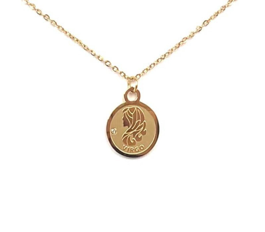 The front side of a gold Virgo Medallion Necklace that features a lady-like symbol on a white background. 