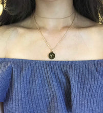 Load image into Gallery viewer, The back side of the gold Aries Zodiac Coin necklace ( Aries Symbol ) worn on a model.
