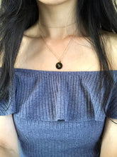 Load image into Gallery viewer, A gold, Capricorn zodiac coin necklace, worn on a model, showing the back side of a Capricorn Medallion necklace with its symbol. 
