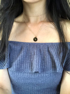 A gold, Capricorn zodiac coin necklace, worn on a model, showing the back side of a Capricorn Medallion necklace with its symbol. 