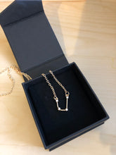 Load image into Gallery viewer, Gold Aquarius Sign Necklace displayed with a black box on a wooden table
