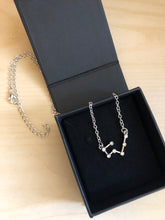 Load image into Gallery viewer, A Silver Taurus Necklaces in a black jewelry box on a light colored wood background.
