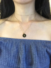 Load image into Gallery viewer, A Leo Zodiac symbol, which is on The back side of the gold Leo Zodiac Coin Necklace is worn on a model.
