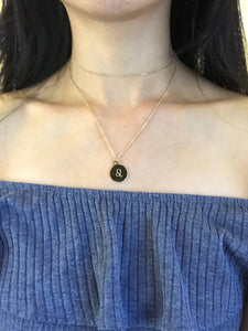 A Leo Zodiac symbol, which is on The back side of the gold Leo Zodiac Coin Necklace is worn on a model.