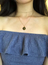 Load image into Gallery viewer, The back side of a gold Pisces Zodiac Sign necklace showcasing the Pisces symbol is worn on a model. 
