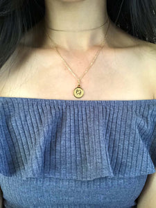 A Gold Pisces Disc Necklace showcasing the front side of the coin is worn on a model.